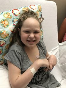 Mary Ashley shows off her new cat-ear headband while sitting in a hospital bed in March 2018.